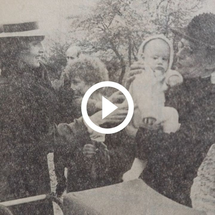 Oude zwart wit foto van slechte kwaliteit met vrouw die baby met wit pakje in handen van Kapelaan Odekerken duwt - playbutton
