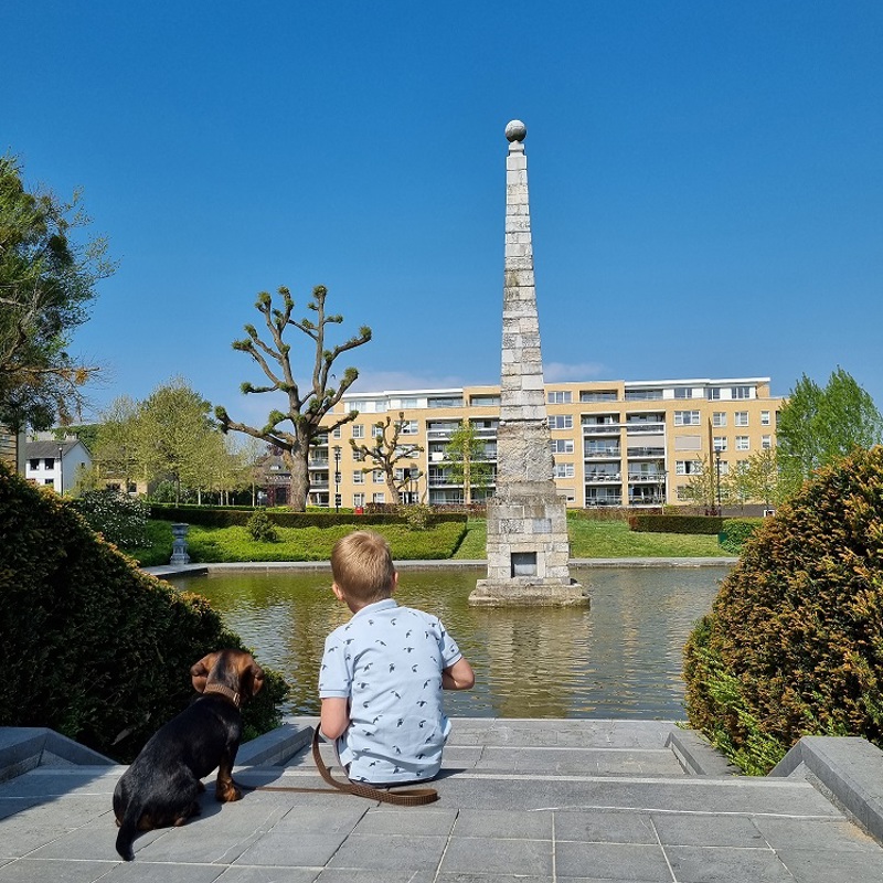 Een kind dat met een hond op een trap zit en kijkt naar een monument in het water