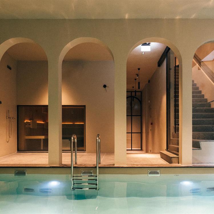 Zwembad met daarachter een sauna in luxe wellness omgeving. 