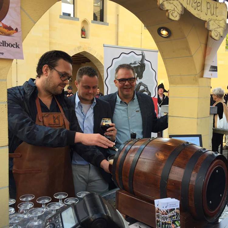 3 mannen tappen speciaal bier uit een liggend houten vat tijdens de Valkenburgse Bokkenweken