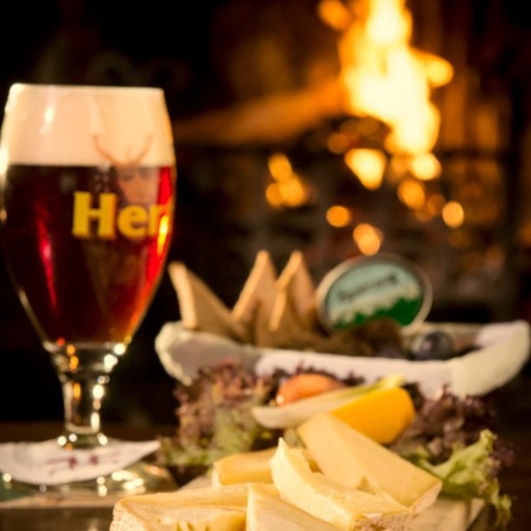 Verse streekproducten en een winters biertje op tafel uitgestald voor een verwarmend haardvuurtje