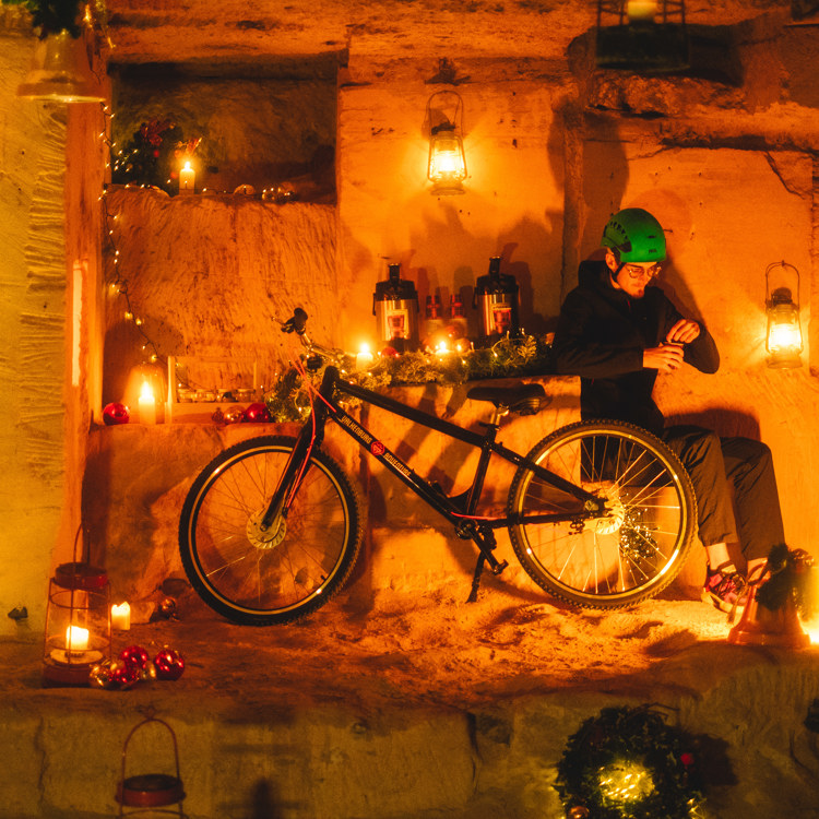 Man met helm naast fiets in een met lampjes versierde mergelgrot