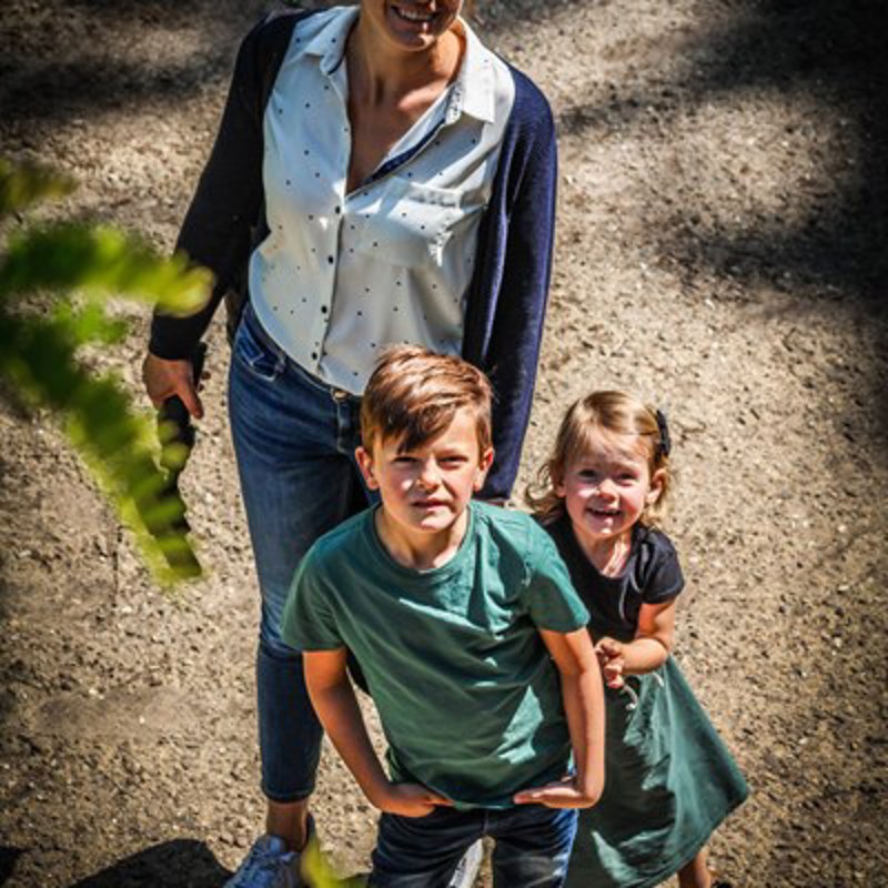 Moeder met twee kindjes kijken omhoog naar de camera