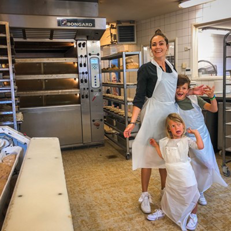 Moeder met twee kinderen in schort poseren in de bakkerij 