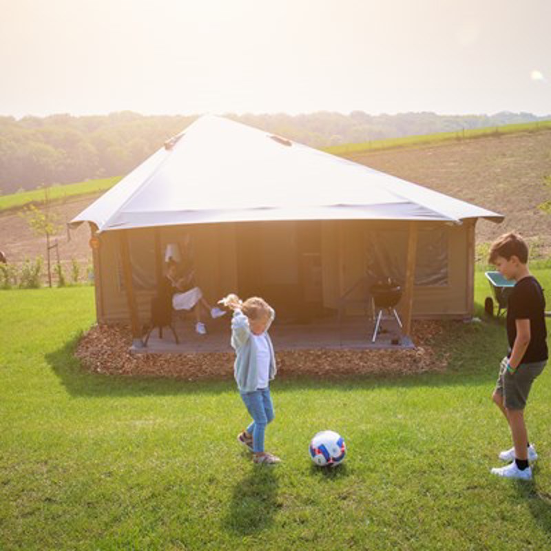 Twee kinderen aan het voetballen op de camping voor de tent. 