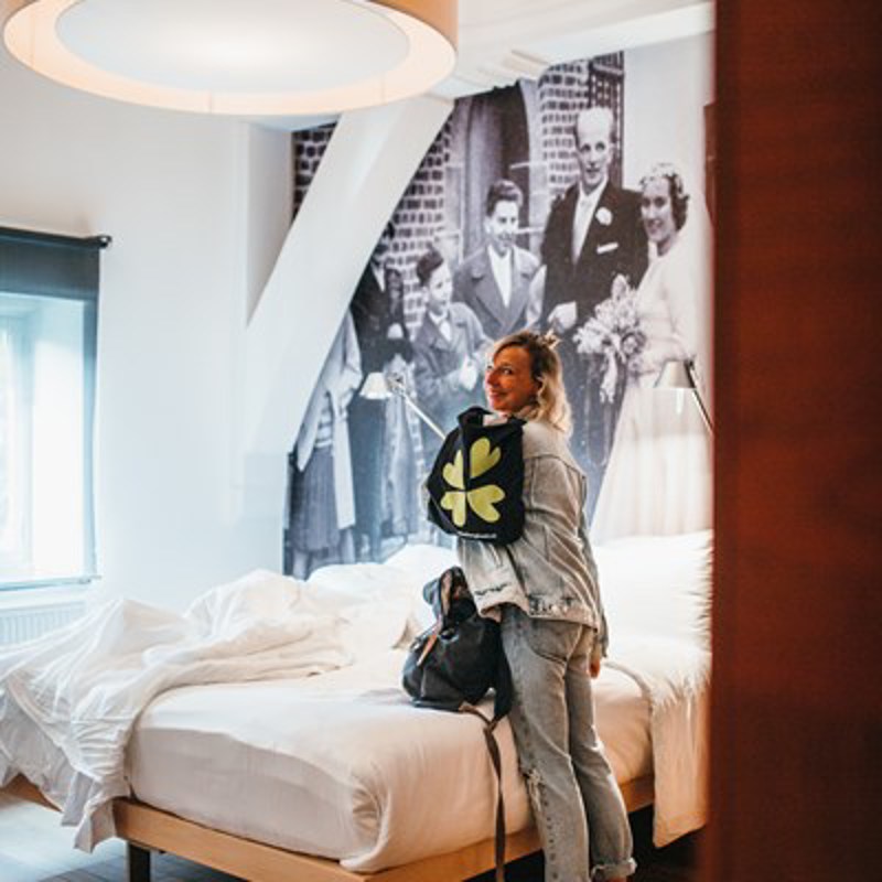 Vrouw in hotelkamer met tas van limburg lonkt