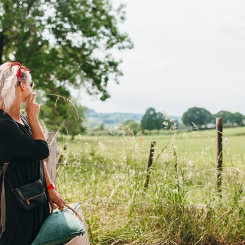 Vrouw met een grasspriet in haar mond kijkend naar het heuvelland