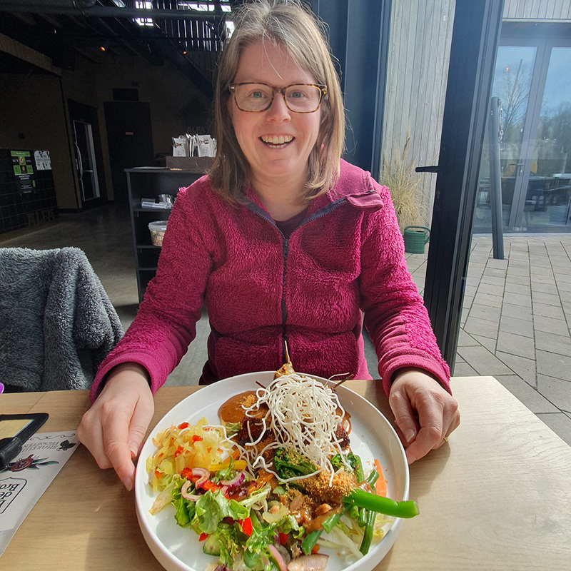 Een vrouw zit aan tafel en heeft een gerecht voor zich om te eten