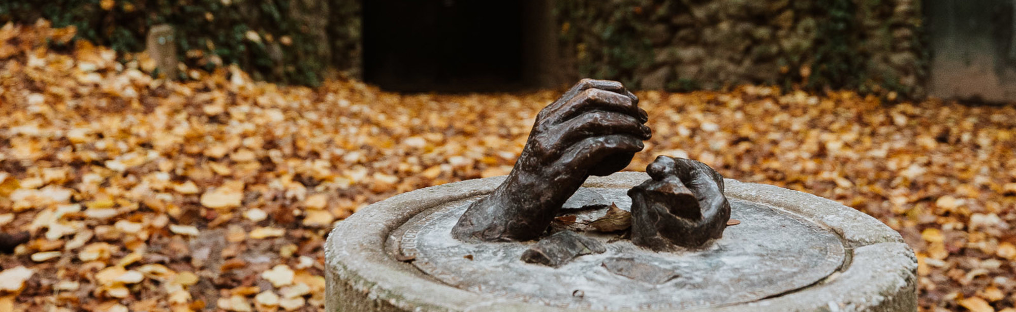 Een beeldhouwwerk met twee handen die vuursteen vasthouden in het bos voor de ingang van de vuursteenmijn 