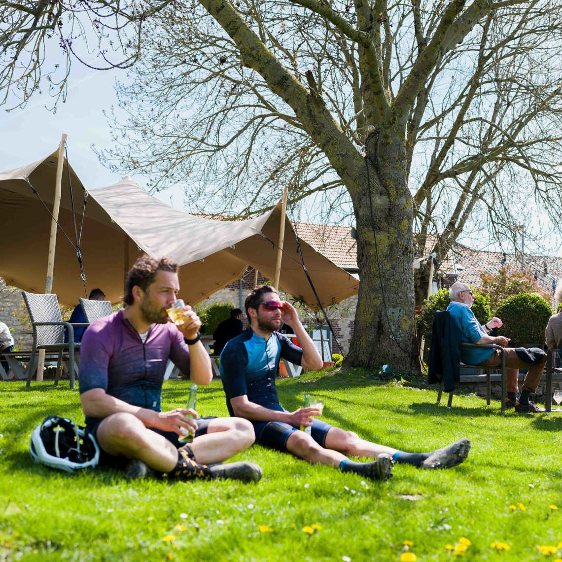 Twee mountainbikers genieten in het gras bij een horecazaakje van iets te drinken