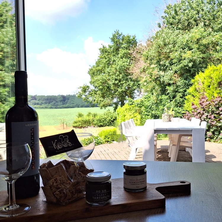 Uitzicht vanaf de dinertafel naar het terras en de tuin van groepsaccommodatie Domein Hellebeuk 