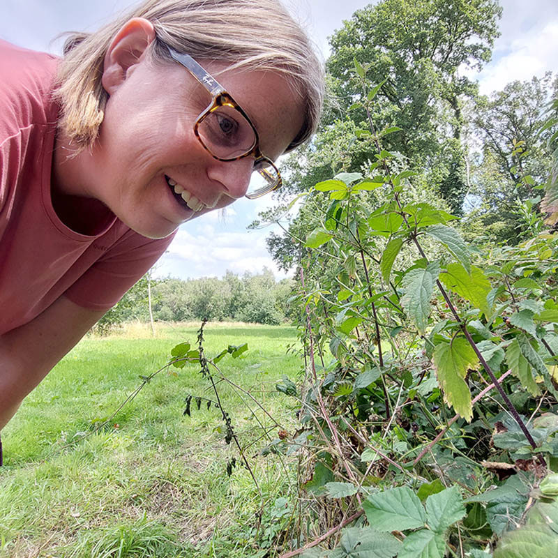 Wandelboswachter Ellen kijkt van dichtbij naar een boomkikker op een groen blaadje