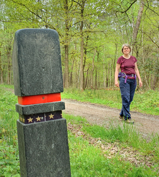 Boswachter Ellen wandelt langs een routepaaltje met 5 sterren in de Schinveldse Bossen