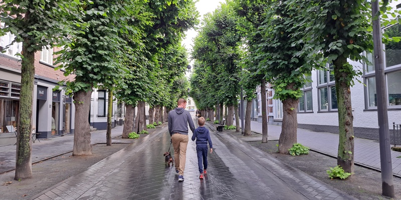 Vader en zoon die door een grijs betegelde straat in Valkenburg lopen