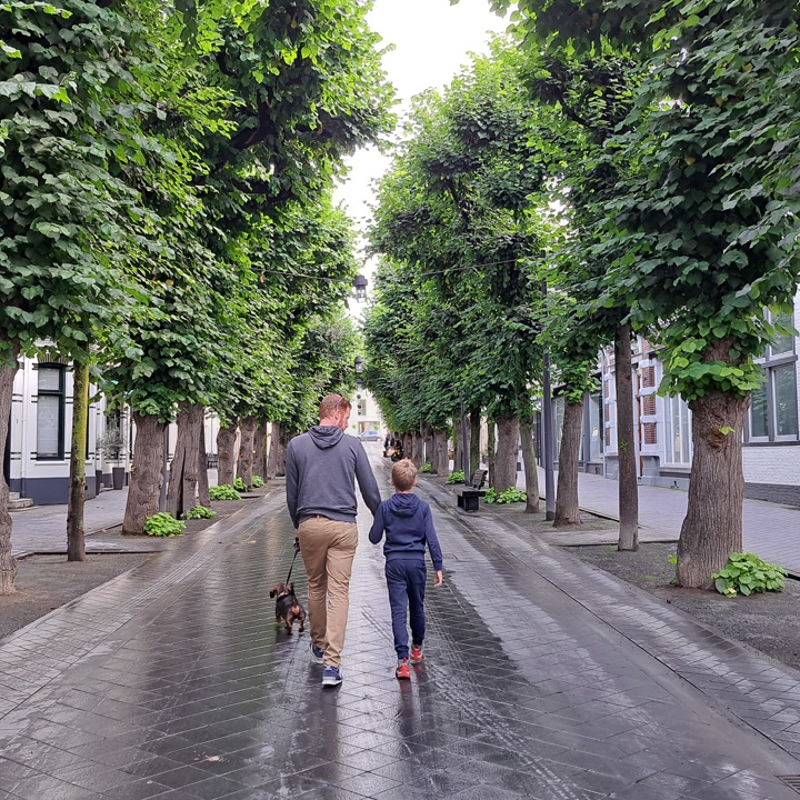 Vader en zoon die door een grijs betegelde straat in Valkenburg lopen