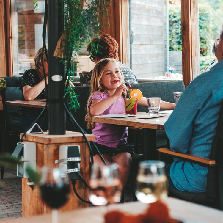 Een vrolijk meisje drinkt een drankje op het terras van Bie de Groeve in Meerssen 