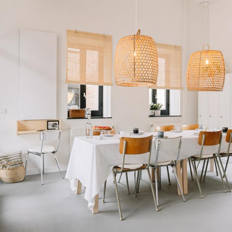 Een Scandinavisch ingerichte eetkamer met acht houten stoelen, een tafelkleed en knusse lampen