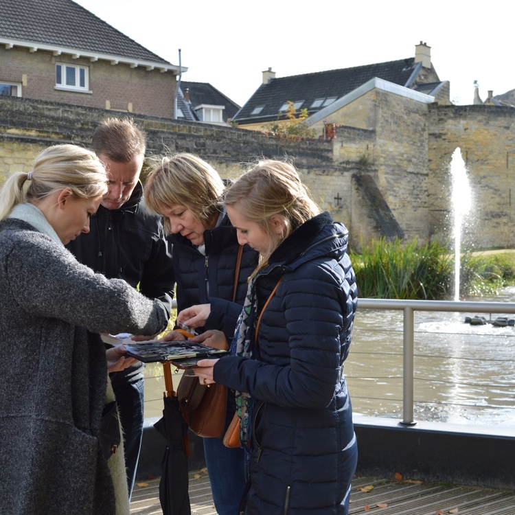 Mensen met winterjassen bekijken samen plankje dat ze samen vasthouden in het Halderpark In Valkenburg