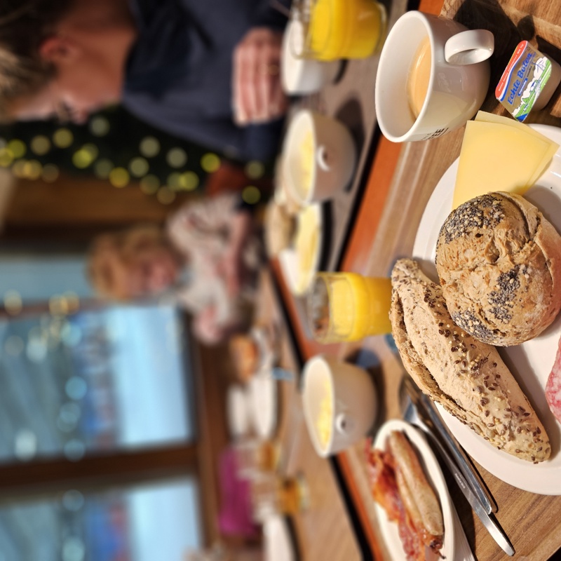 Ontbijt op tafel met daarachter een doorkijkje naar de piste. 