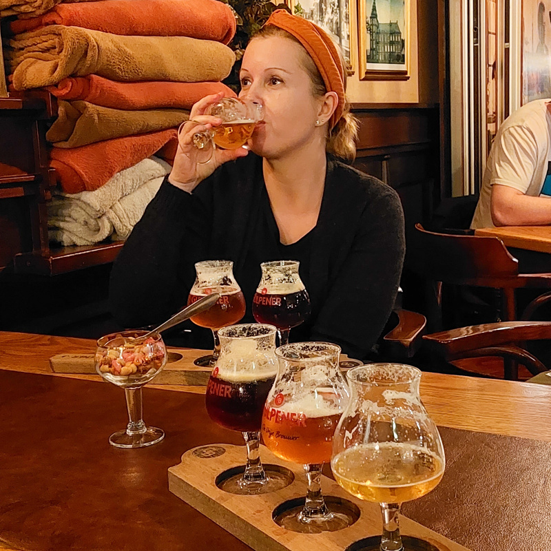 Dame geniet van een speciaalbiertje in een bruin gezellig cafe. 