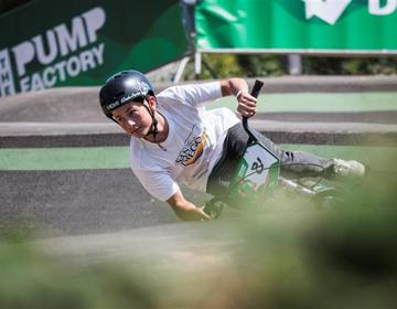 Jongen op BMX gaat bijna horizontaal door de bocht