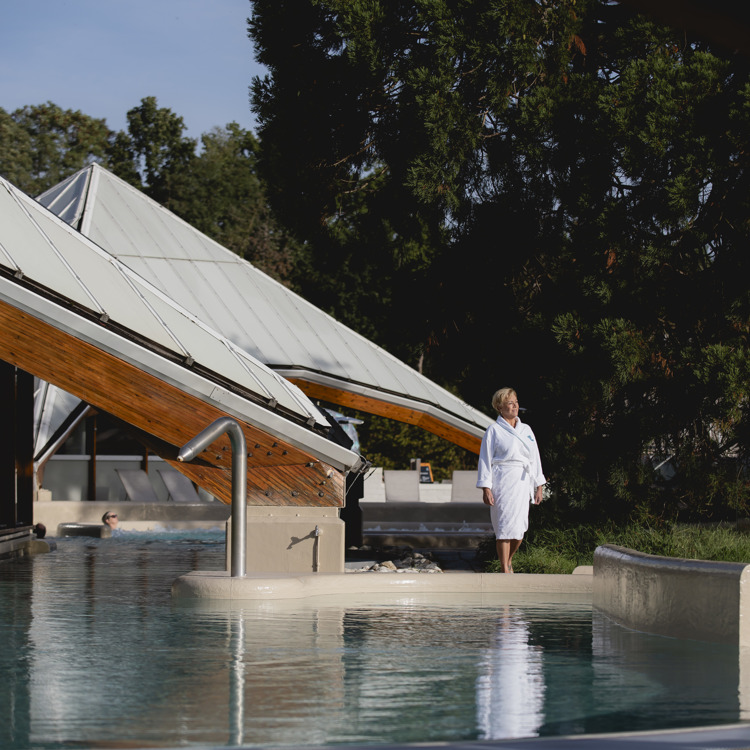 Vrouw in badjas bij buitenbad bij Thermae 2000