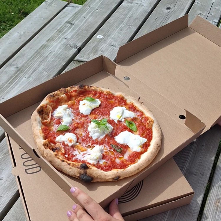 Pizza in doos op een van de picknickbanken bij Hoeve Cobelli