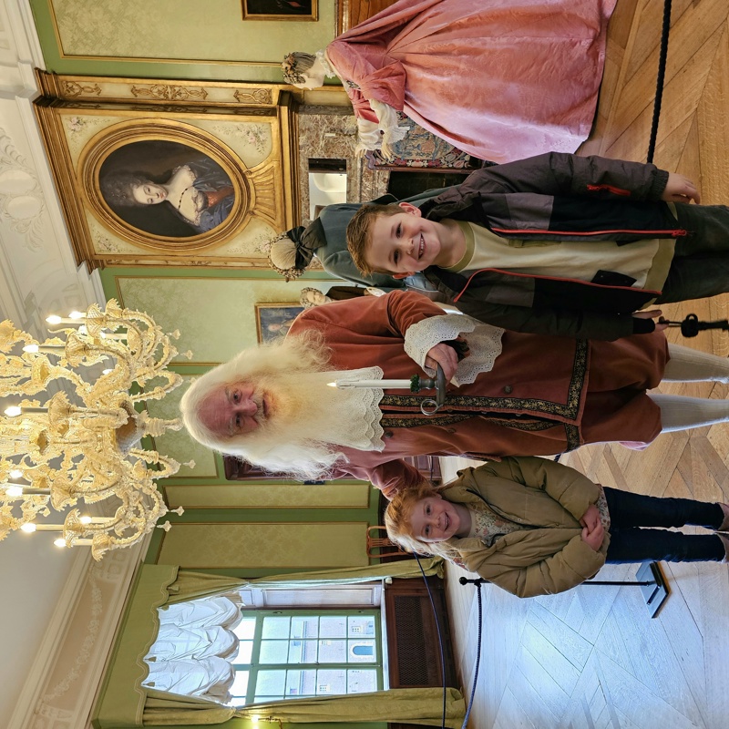 Twee kinderen op de foto met een oude bewoner van het kasteel. 