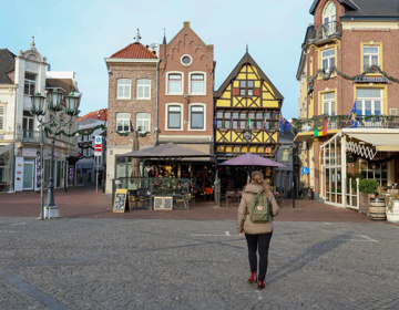 Vrouw loopt over de mark in sittard met diverse restaurants. 