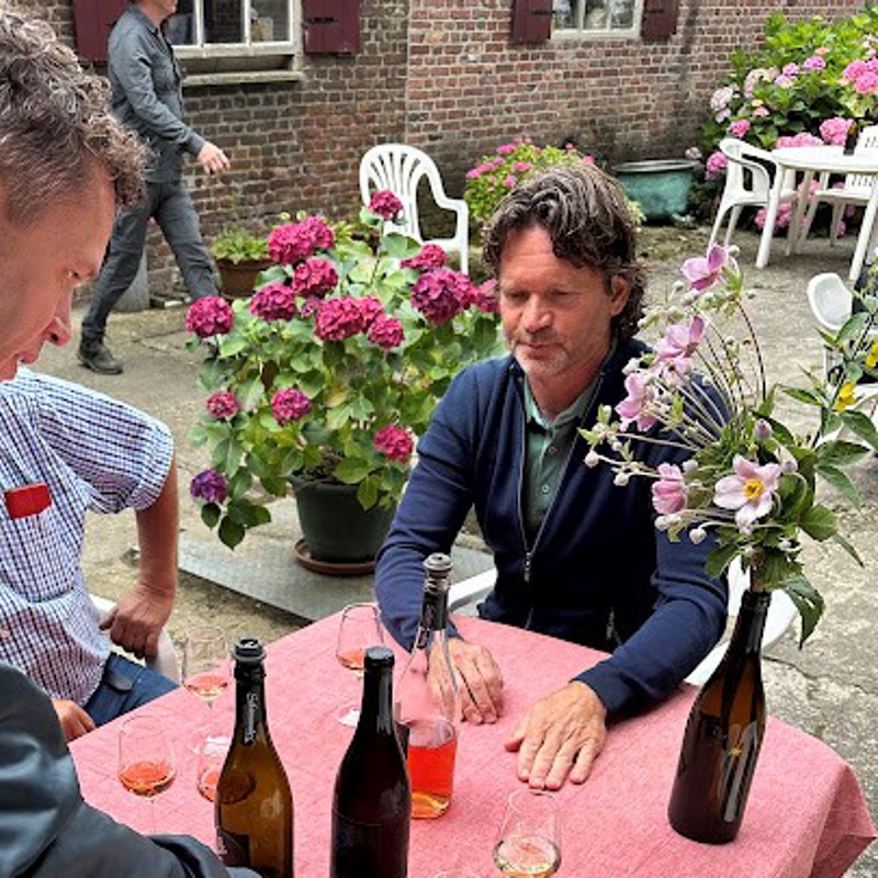 Sander zit aan tafel bij Domaine Salamander terwijl er wijn naar de tafel wordt gebracht. 