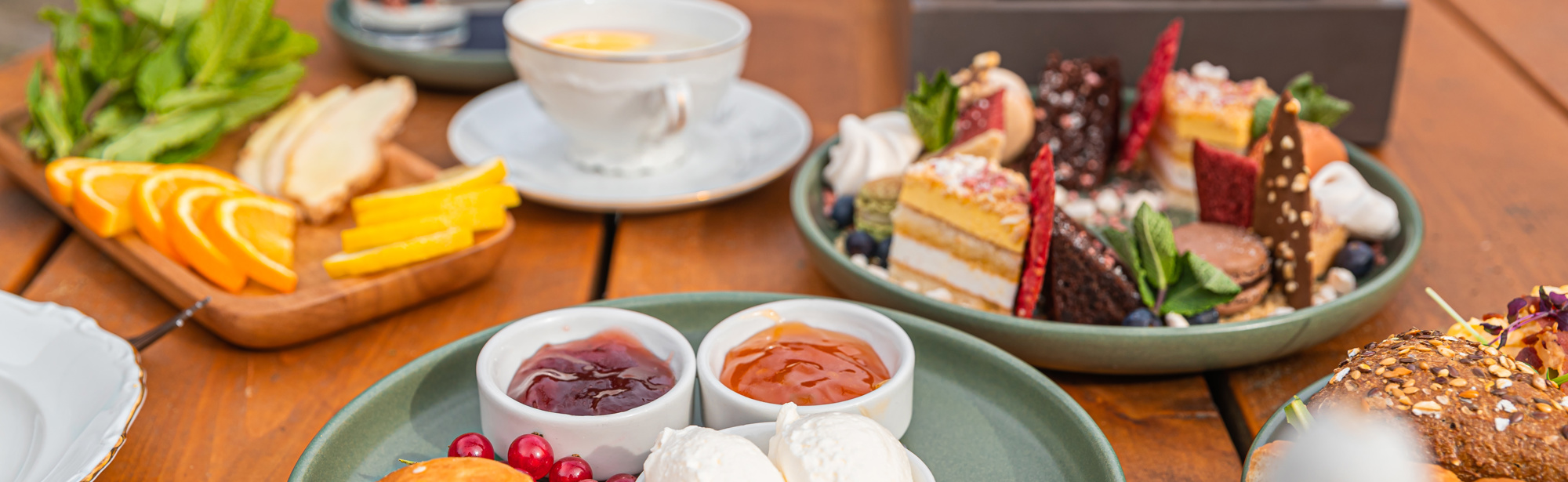 Tafel vol met lekkernijen, scones en een grote kan thee. 