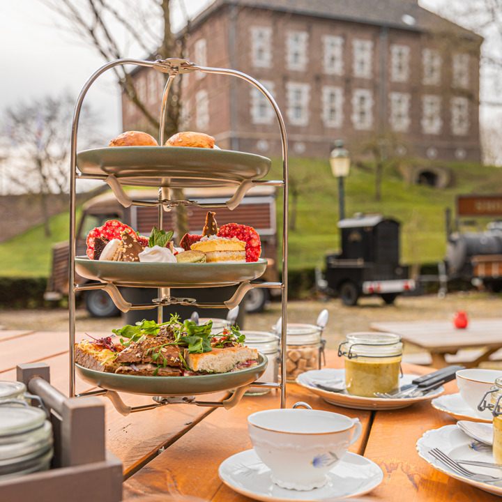 Tafel met uitgestalde high-tea op de binnenplaats van Kasteel Limbricht. 