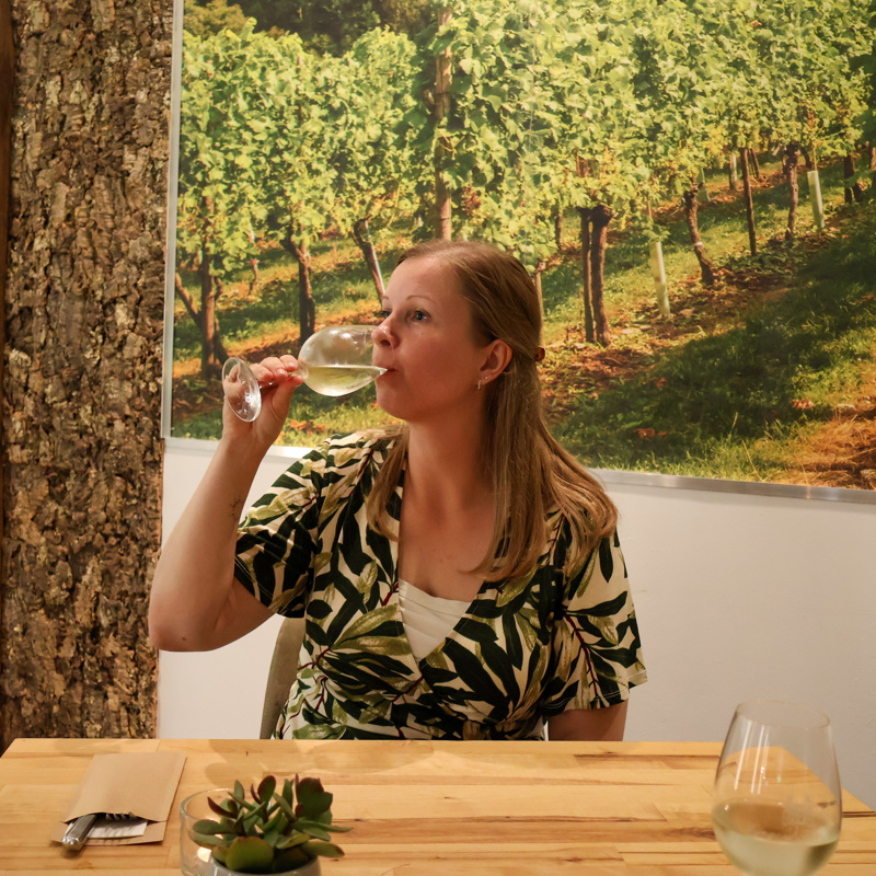 Kim neemt een slokje van een glas witte wijn in het proeflokaal bij Fromberg. 