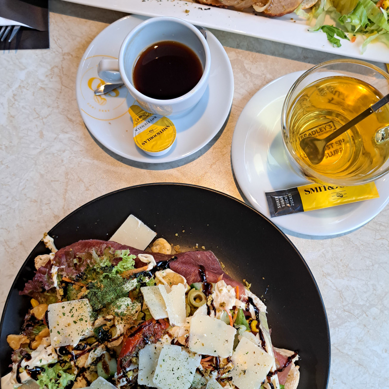 Bovenaanzicht van twee lunchgerechten met koffie en thee erbij. 