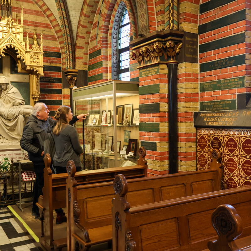 Man en vrouw staan voor vitrine in een basiliek. 