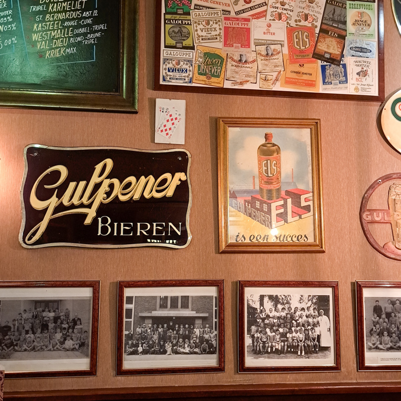 Interieur van een klassiek bruincafe met oude foto's en etiketten aan de muur. 