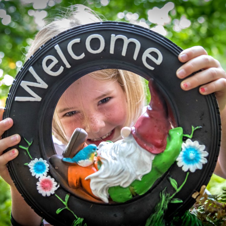 Meisje kijkt door welkomstornament met kabouter