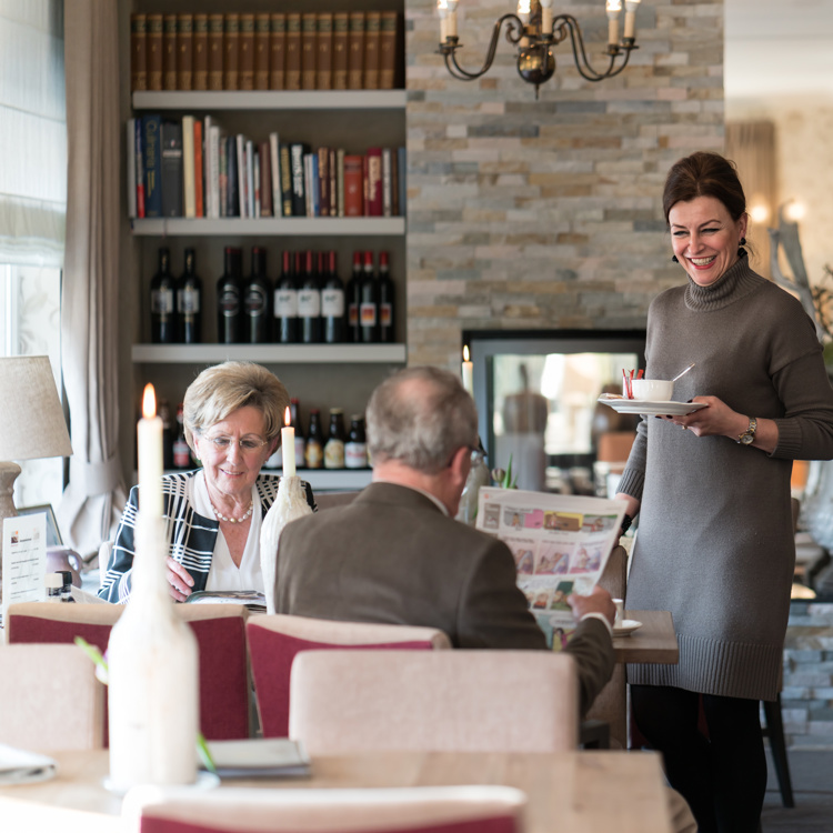 Vriendelijke dame van Landhotel Heuvelzicht brengt een ouder echtpaar een kop soep in het bijbehorende hotelrestaurant. 