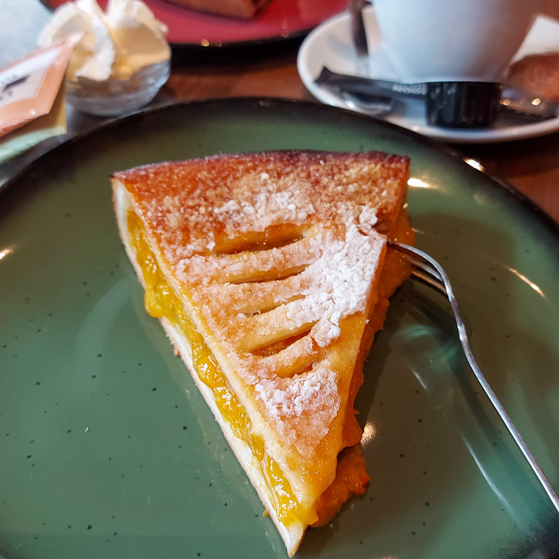  Stukje abrikozenvlaai op een schoteltje met een vorkje. 