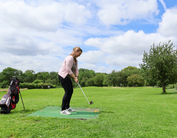 Dame is aan het golfen in een groene omgeving. 