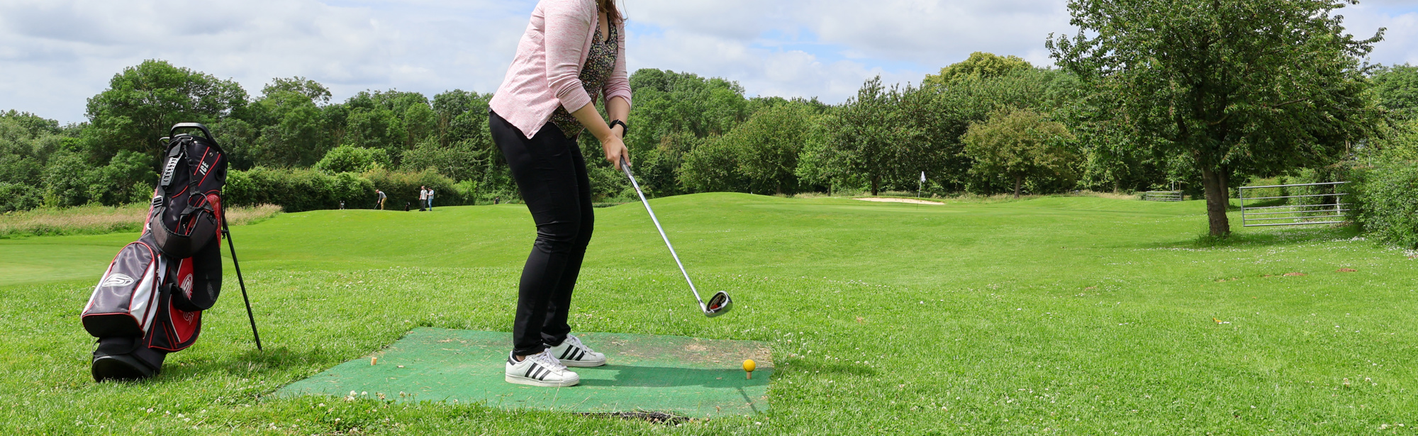 Dame is aan het golfen in een groene omgeving. 