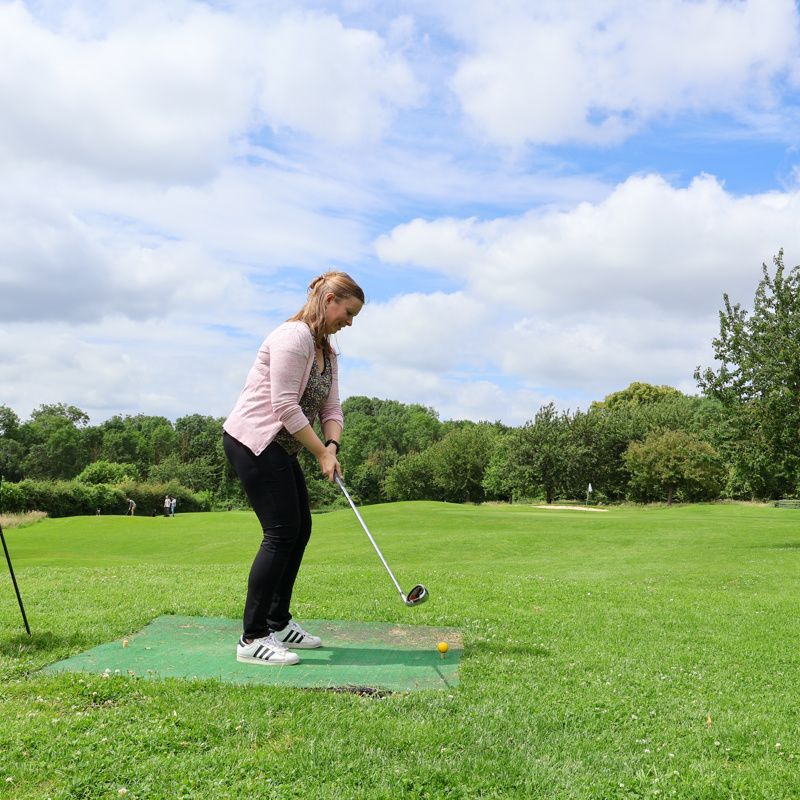 Dame is aan het golfen in een groene omgeving. 